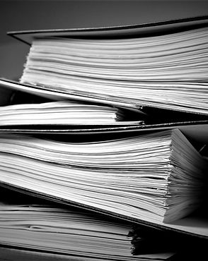 Close-up of a stack of thick, open folders filled with documents.