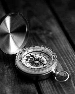 Vintage compass with an open lid on a wooden surface.